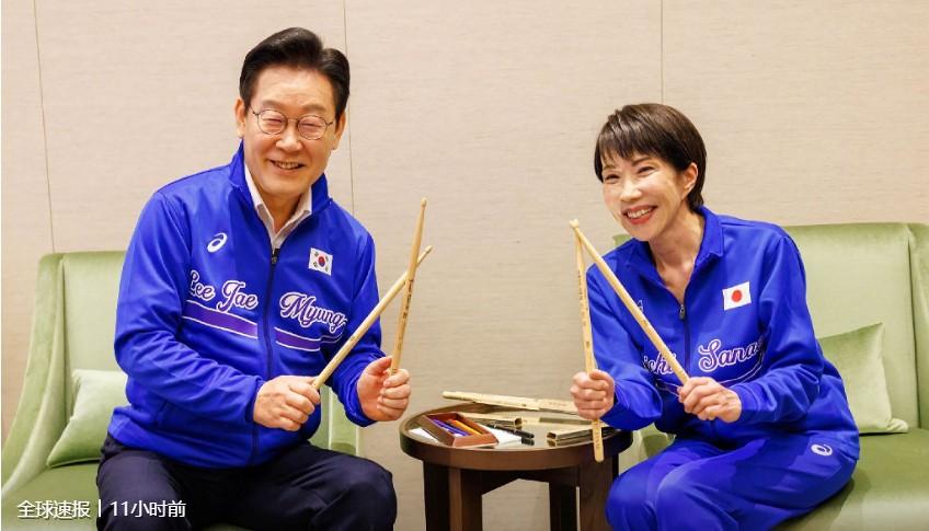 两个人在玩什么游戏？

原来是在打架子鼓。
寓意是，
李在明要敲打一下高屎早苗，