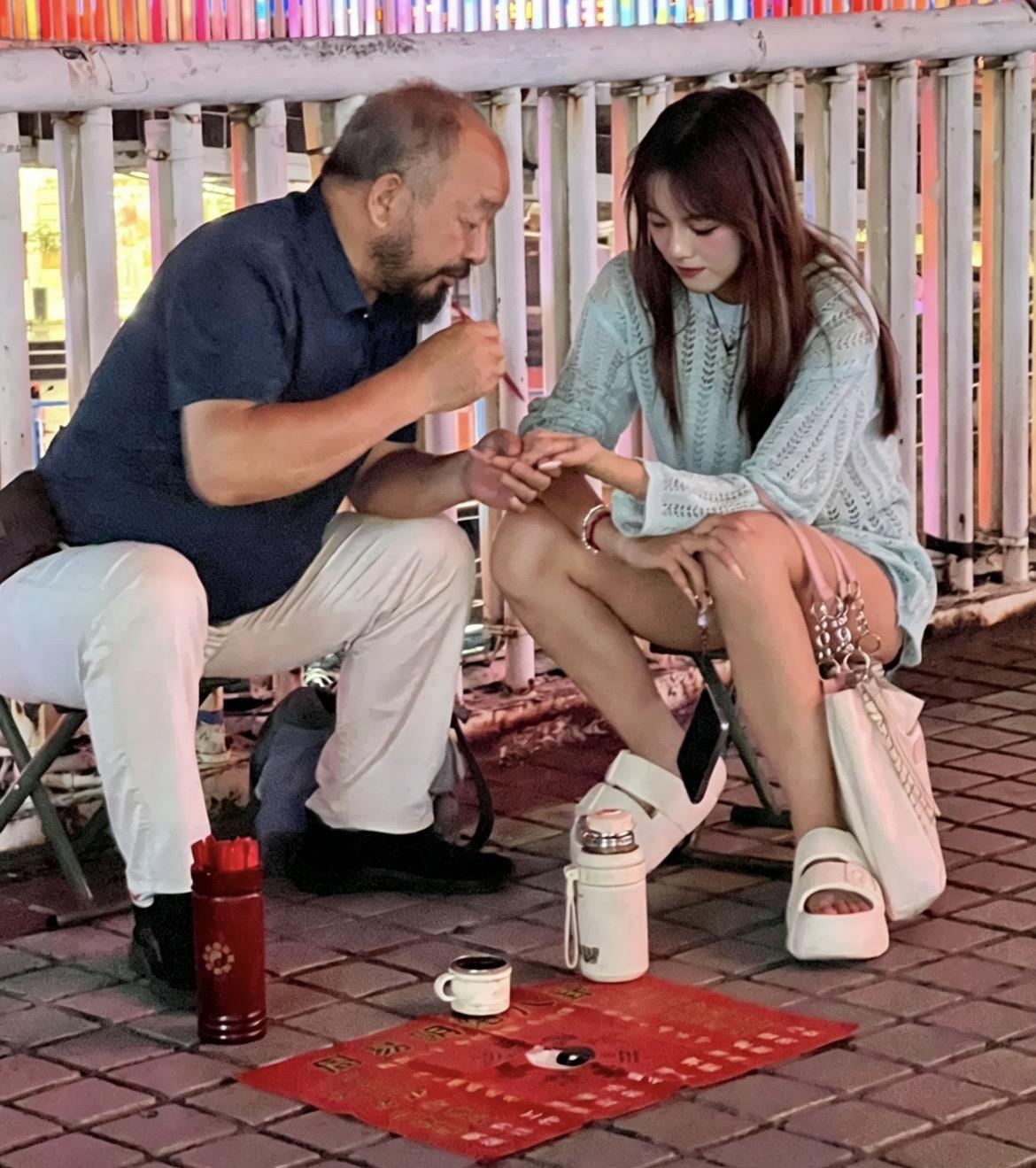 城市天桥上一位风水大师正在为一位妙龄女子看手相，我留意着女子的表情，风水大师时而
