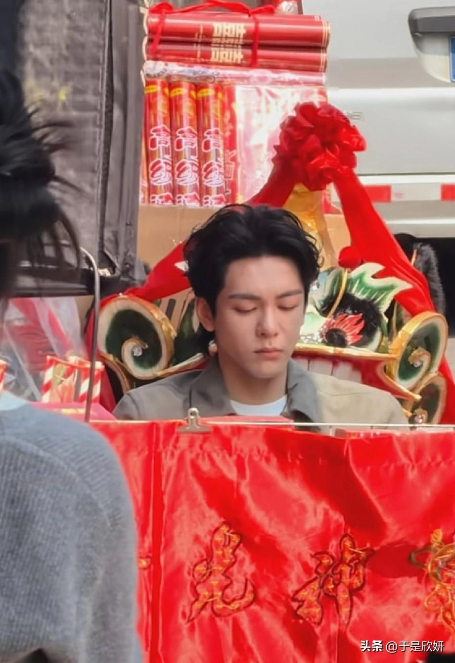 曾舜晞新剧路透曝光，他坐在装饰喜庆的神轿里，周围挂满红绸鞭炮，被众人抬着逛集市，