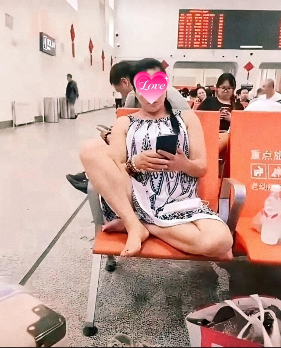 候车厅里，她赤足蜷坐，目光低垂刷着手机。这姿势，旁人看了或许别扭，她自己却浑然不