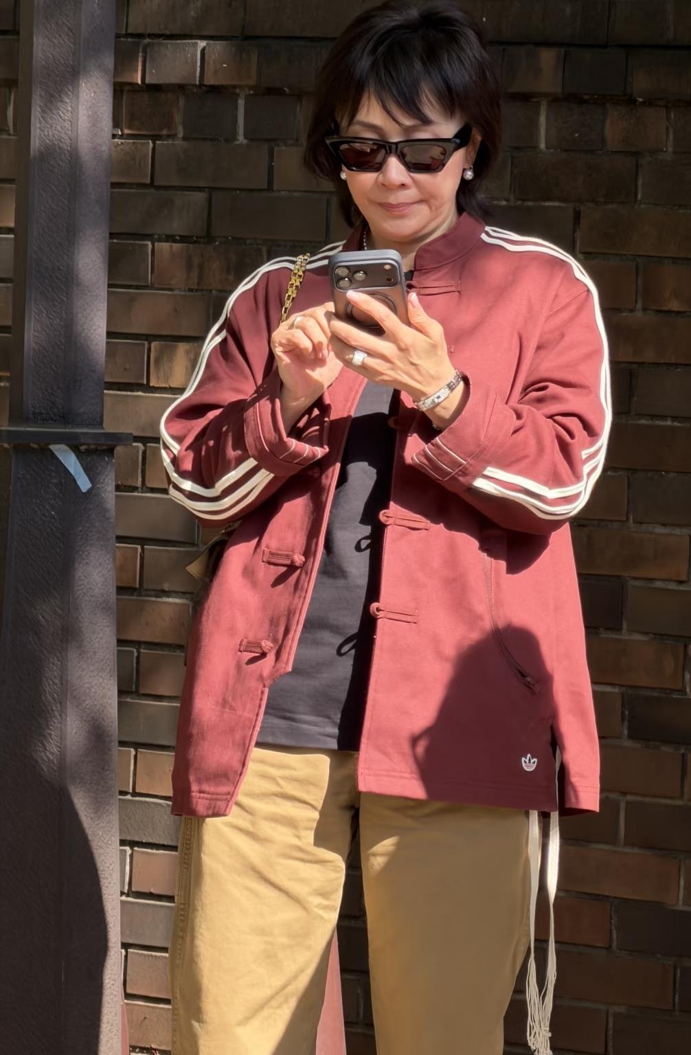 61岁刘嘉玲在东京六义园被偶遇拍到，她身穿红色中式外套搭配咖色休闲裤，佩戴大钻戒