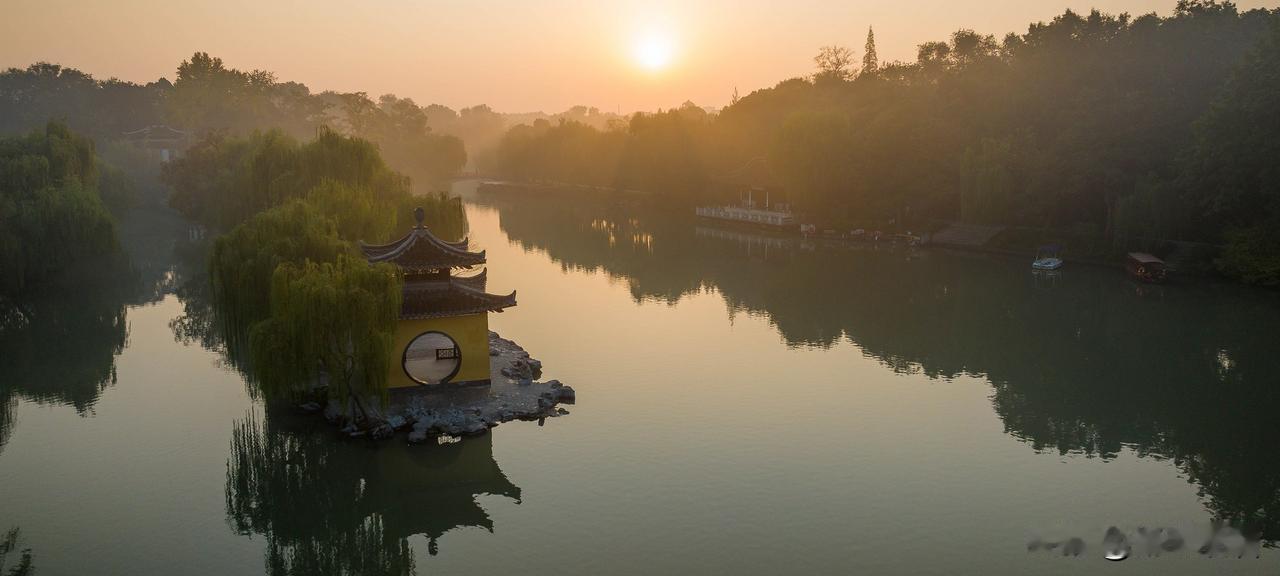 清晨的扬州瘦西湖钓鱼台，静谧而美丽，宛如一幅淡雅的水墨画。阳光透过晨雾洒在湖面上