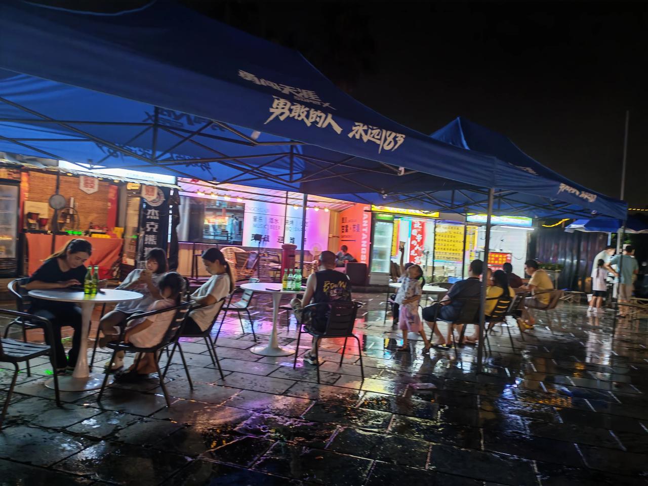 夜市烟火
 
雨后的夜晚，地面还留着湿漉漉的水光，倒映出街边斑斓的霓虹，氛围感瞬