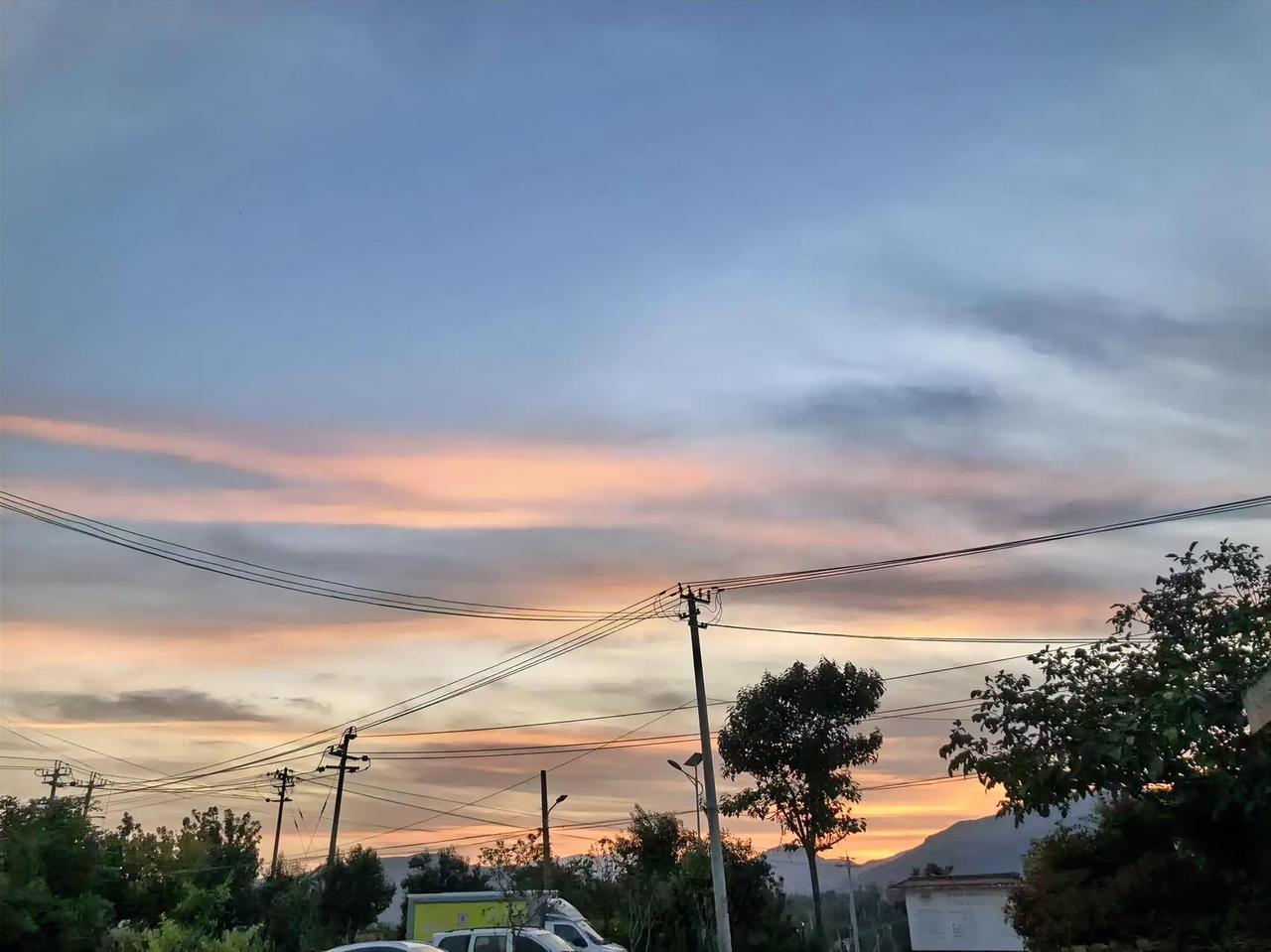 风把日头吹矮的时候，我趴在窗台看这片晚霞——像有人在天边铺了层揉碎的橘子糖，粉橙