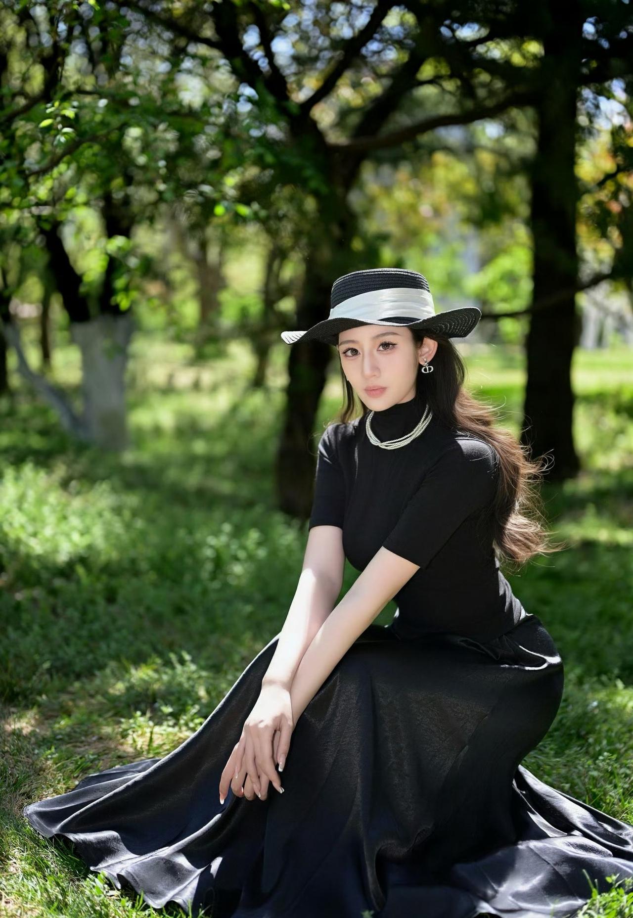 黑裙衬绿意，光影落肩头。

一身简约高级的经典黑，把优雅与清冷稳稳拿捏。

林间