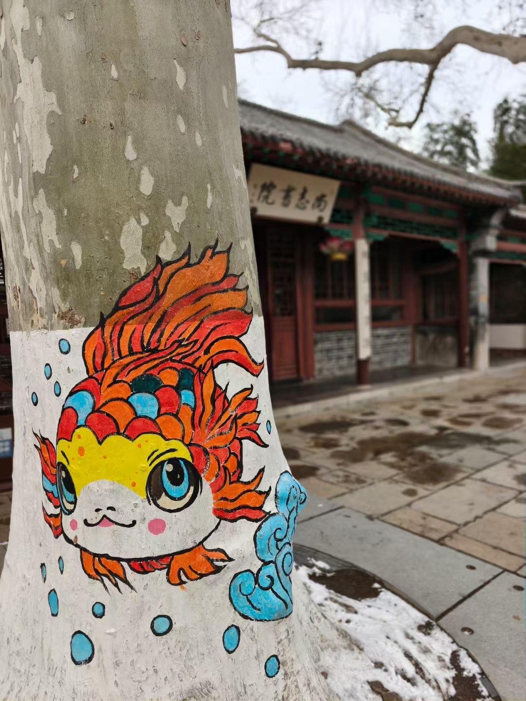 《树绘金鱼》

树干苍苍绘锦鲤，
鬈须焕彩韵悠长。
圆睛炯炯灵光闪，
鳞片斑斓绮