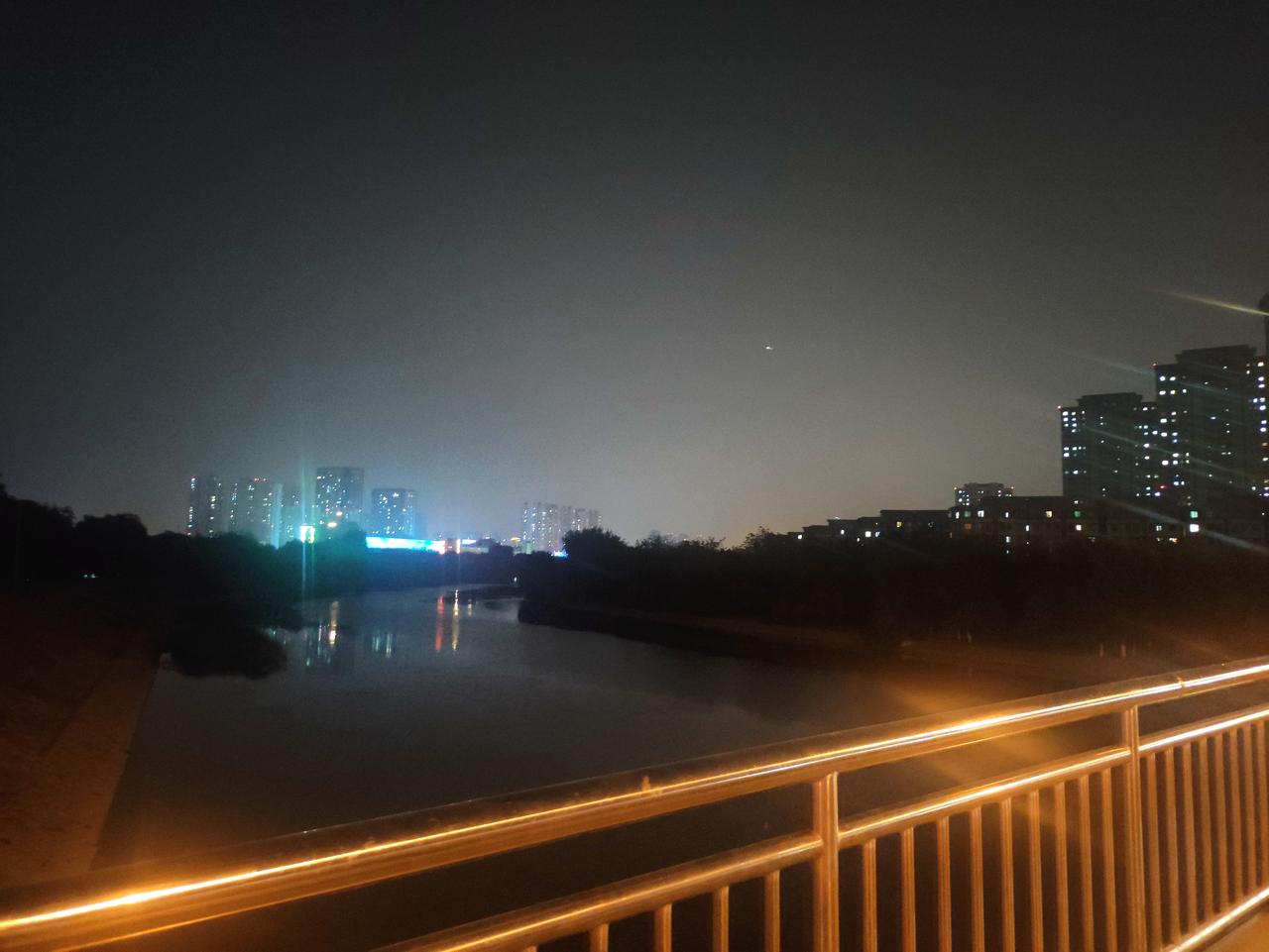 夜幕下的城市河景，灯火阑珊，车流如织。
