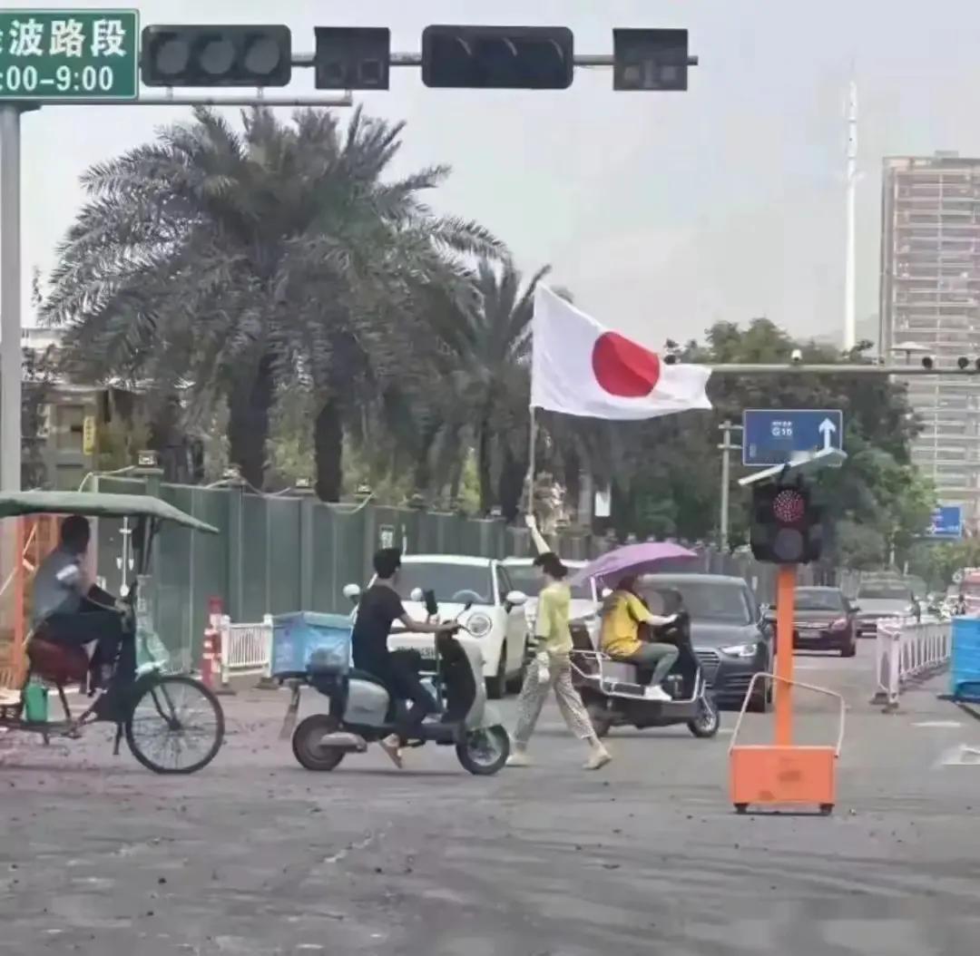 浙江温州一女子高举日本旗大摇大摆走过路口，全程竟无一人上去阻拦！