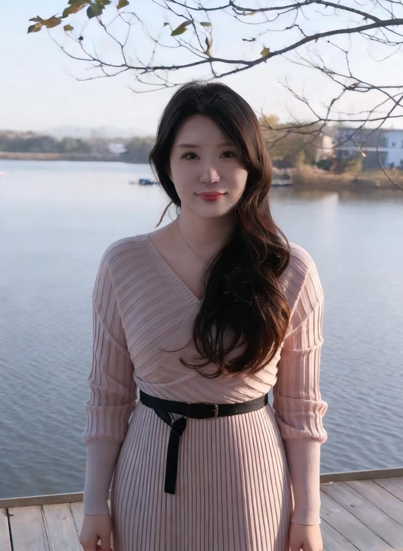 粉裙束带立湖头，卷发轻垂映碧流。
一笑春风吻水面，眸光清似镜湖秋。