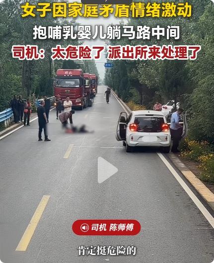 河南洛阳，一名身穿黑衣女子，怀抱婴儿横躺在马路中间，当时道路车来车往，该母子躺在