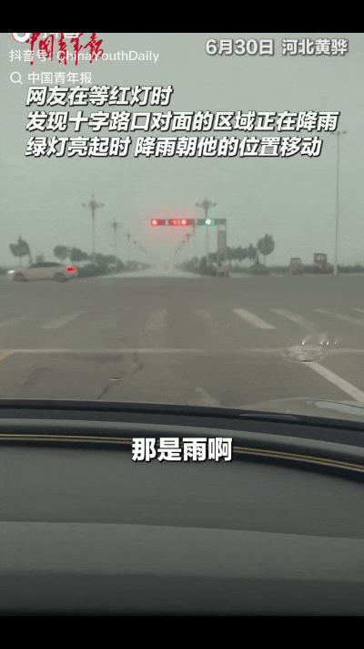 “太神奇了！”河北黄骅，网友开车在等红绿灯时，发现十字路口对面域在下雨，绿灯亮起