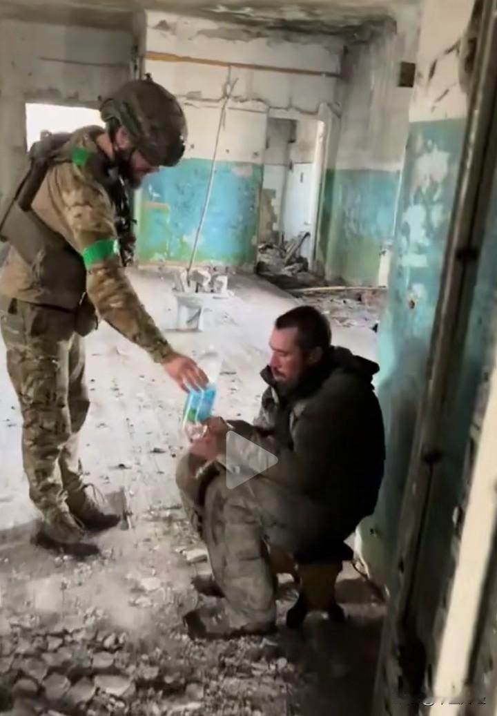 在一座被打的七零八落的房间内，一名乌克兰士兵给抓捕的俄军士兵矿泉水，这名士兵忐忑