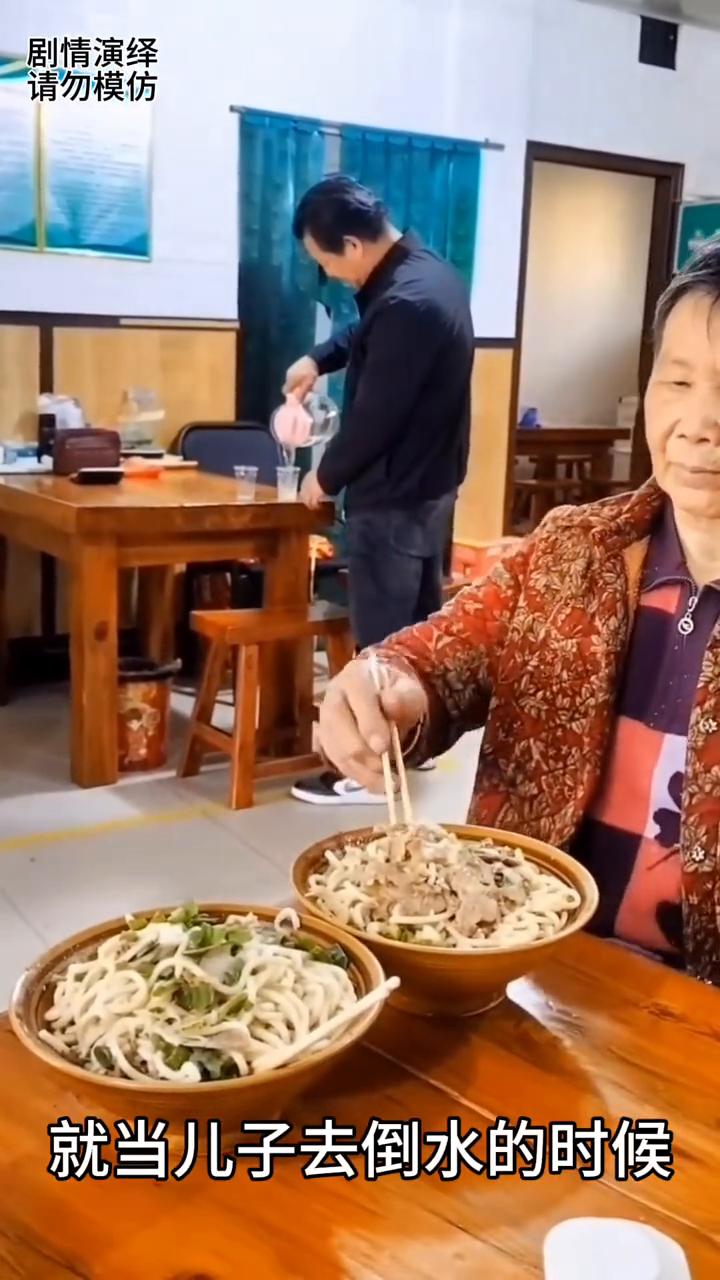 母亲给儿子碗里夹肉吃，这一幕真的太感人了。
母子两个在饭店吃面，就当儿子去倒水的