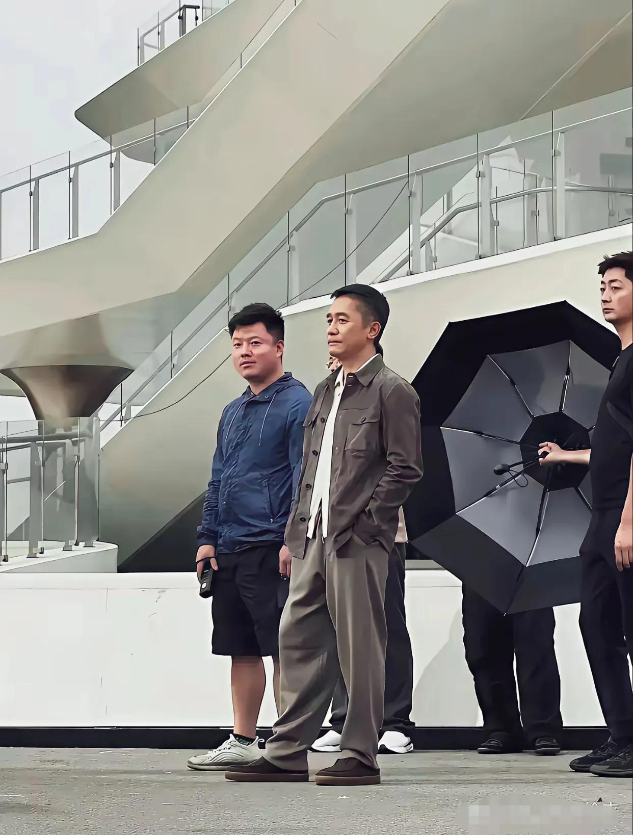 梁朝伟后面那个人拿的什么伞，也没下雨，也没太阳，不会是拍照用的吧！