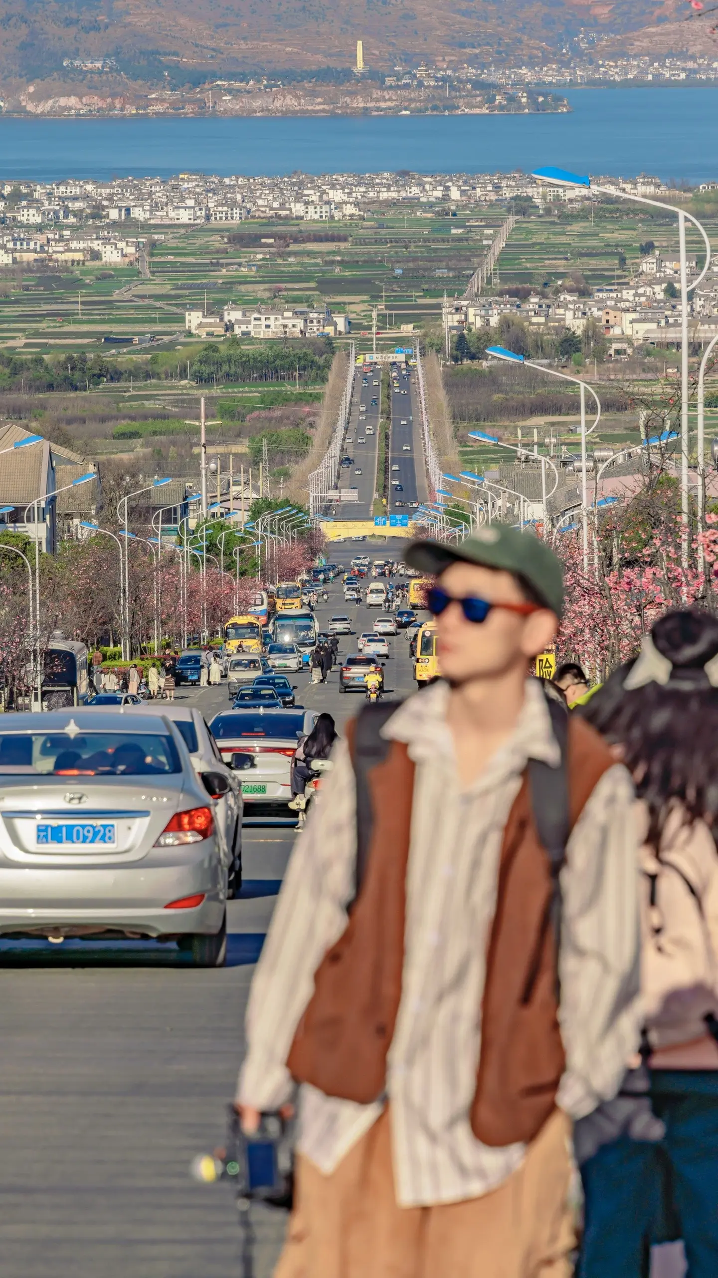 打卡大理网红公路弘圣路。这条通往洱海的公路两边都开满了花🌸，下午4点以后拍照效果超美～
阳光洒在洱海上，波光粼粼的感觉让人心情超好！😃 
这个季节弘圣路两边的桃花也盛开啦！每天都有很多人在这里拍照，可以拍虚实人物的特写，把公路、洱海、大山和桃花都收进画面，照片更有故事感哦！
⚠️记得安全第一哦，拍照时用长焦，压缩马路景深感，绝对是绝美风景！
📷我用的相机：索尼a7R3➕28-200
📍拍摄地点：就在大理古城附近，下午五点左右拍最美！ 
🚥关于交通：
方便一点的话建议到达大理后租一辆🛵电瓶车骑行，（这个季节风吹着很舒适，不冷不热，特别适合春游哦！）
🌸快来感受大理弘圣路带给你的视觉盛宴吧！
