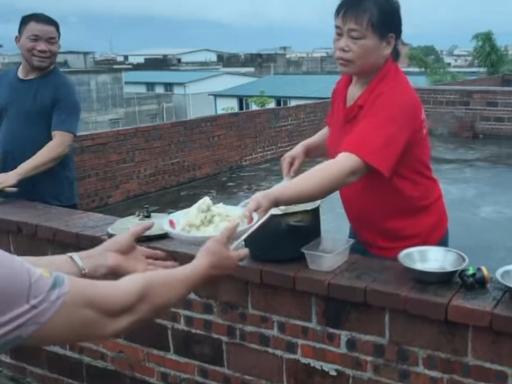 洪水中，一碗热饭递上天台，子女才敢放心。洪水围困下，邻居把热饭通过天台传给被困父