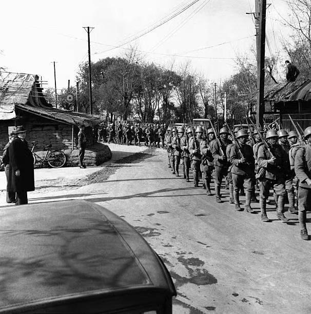 图一：1937年，淞沪会战期间，日寇士兵正列队行进在街头。看周边有租界士兵警戒