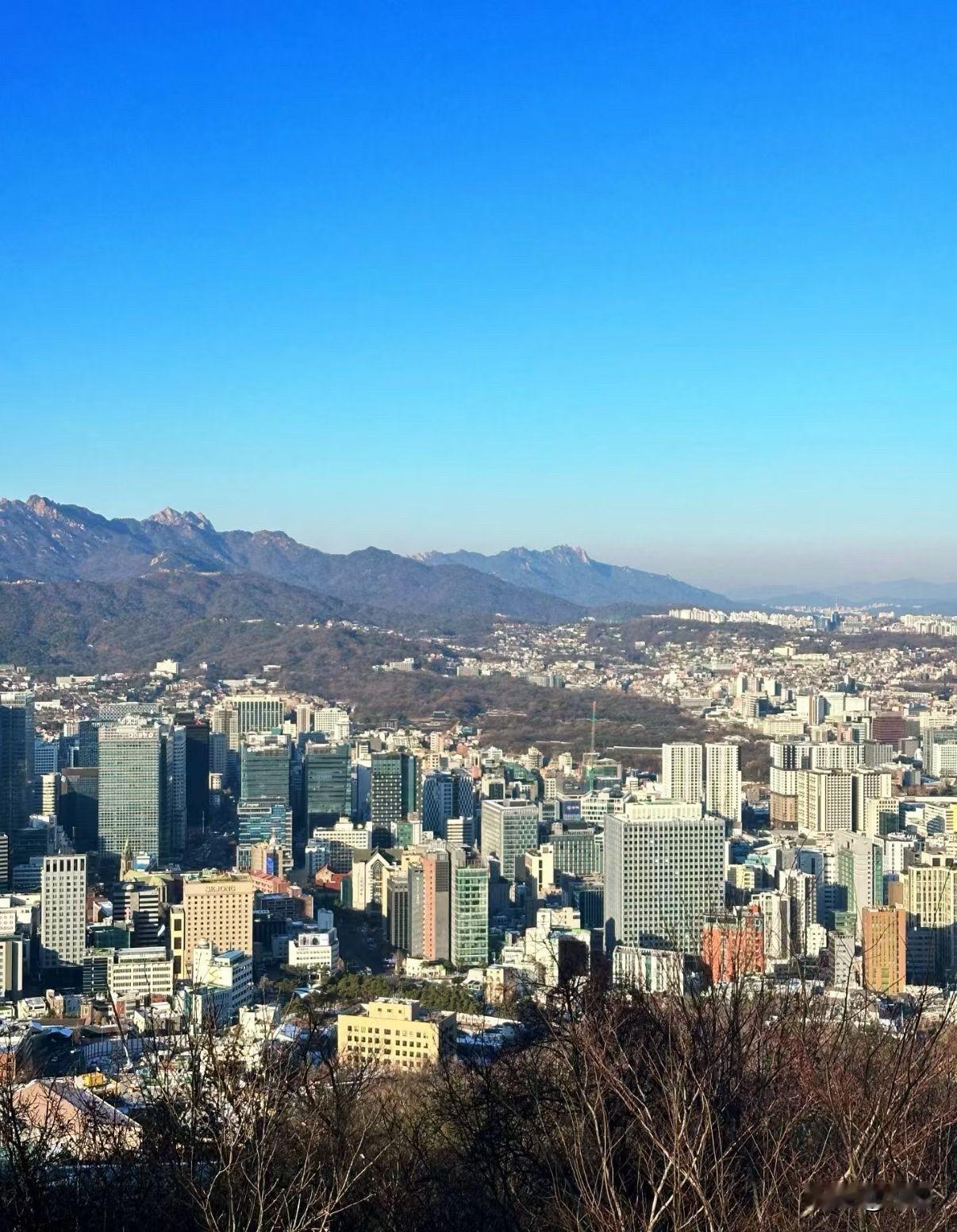 站在首尔的山坡上往下望，整座城市就这么铺展在眼前，高楼挨着高楼，密密麻麻却又透着