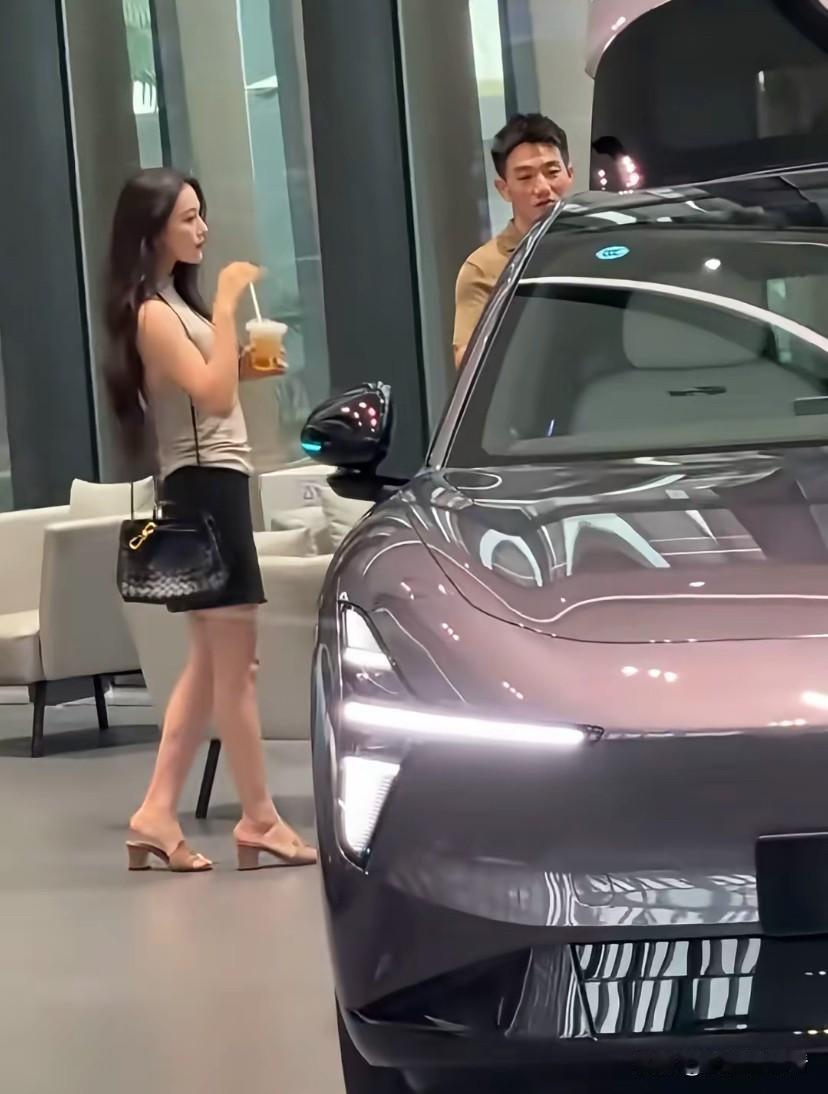 张馨予陪老公看新能源电车，老公何捷在一边仔细观摩，张馨予则在一边喝着饮料盯着老公