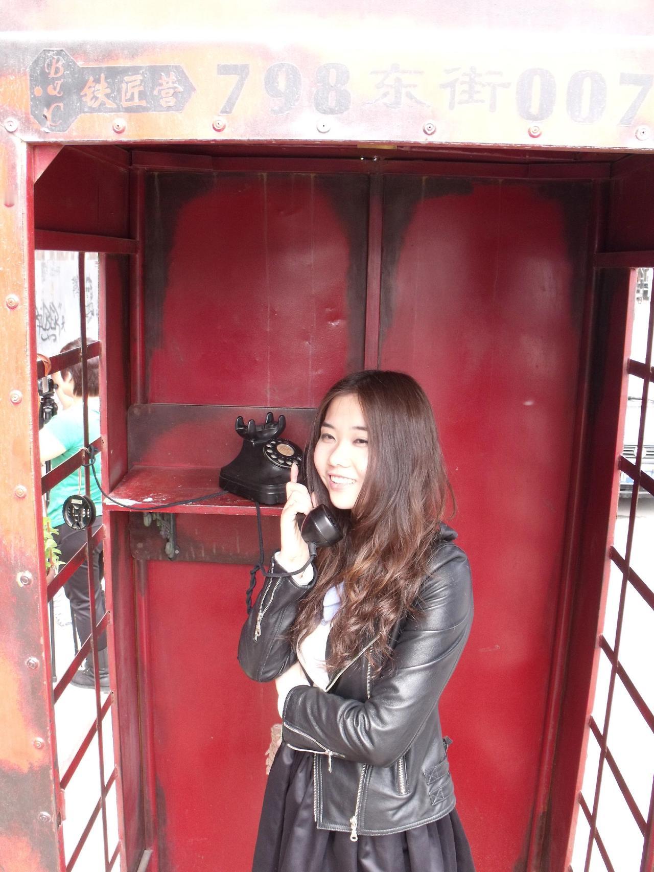 📞复古电话亭里藏着时光机？☎️红漆剥落像岁月吻过的唇，皮衣少女正和90年代煲电