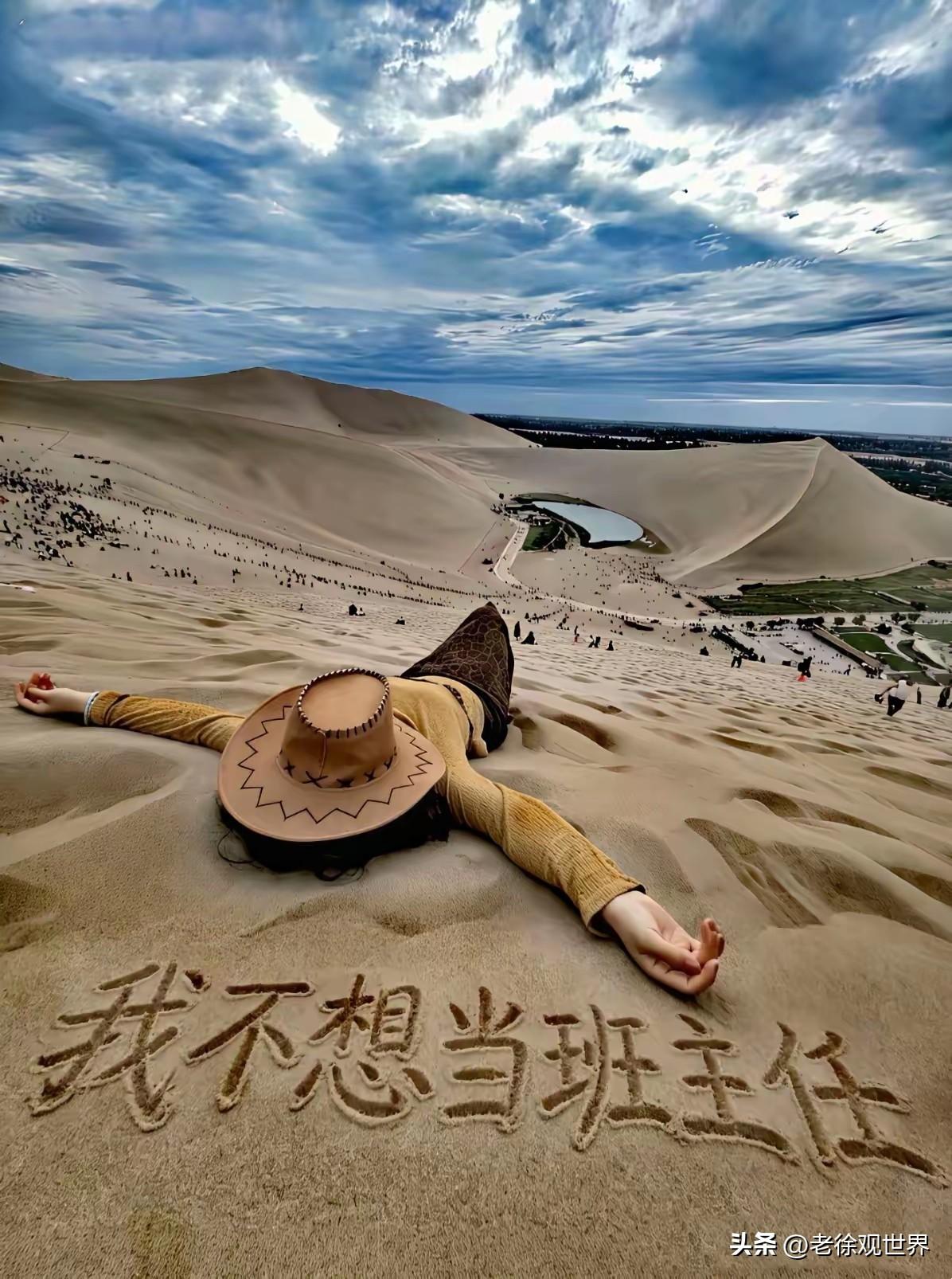 甘肃鸣沙山，一位年轻女老师躺在大漠沙丘上，在黄沙写下大字：我不想当班主任。

一