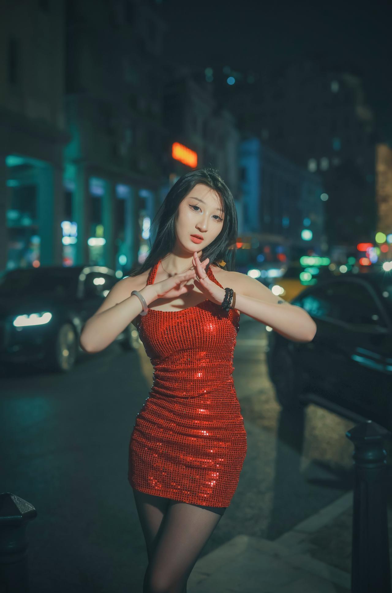 身穿红衣的女子，优雅地站在月光下，她在夜的幕布下散发出一种迷人的韵味，令人陶醉。