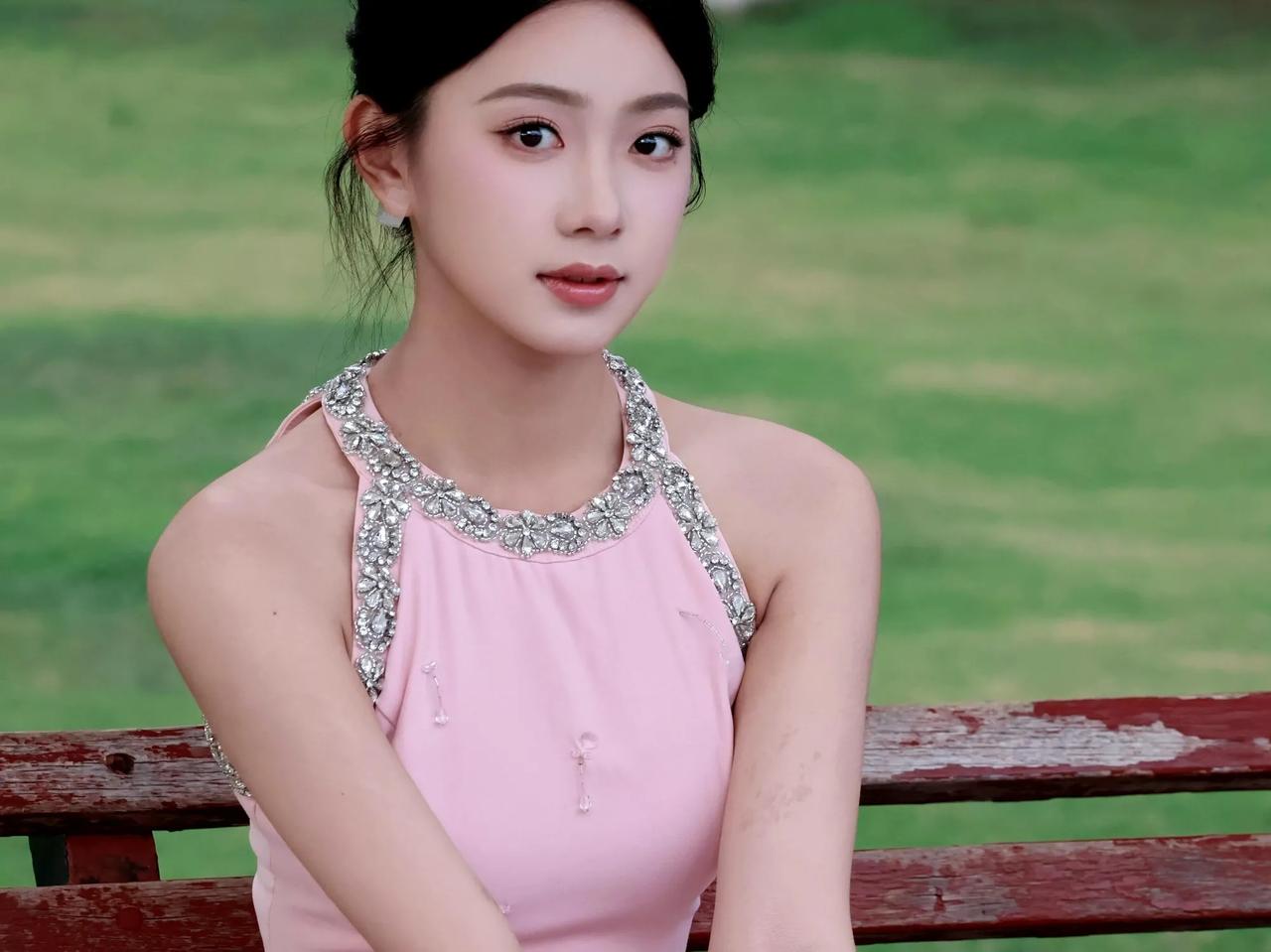 夏日清新少女，粉色连衣裙搭配闪亮项链，坐在绿草地上，甜美动人。你心中的美女啥模样