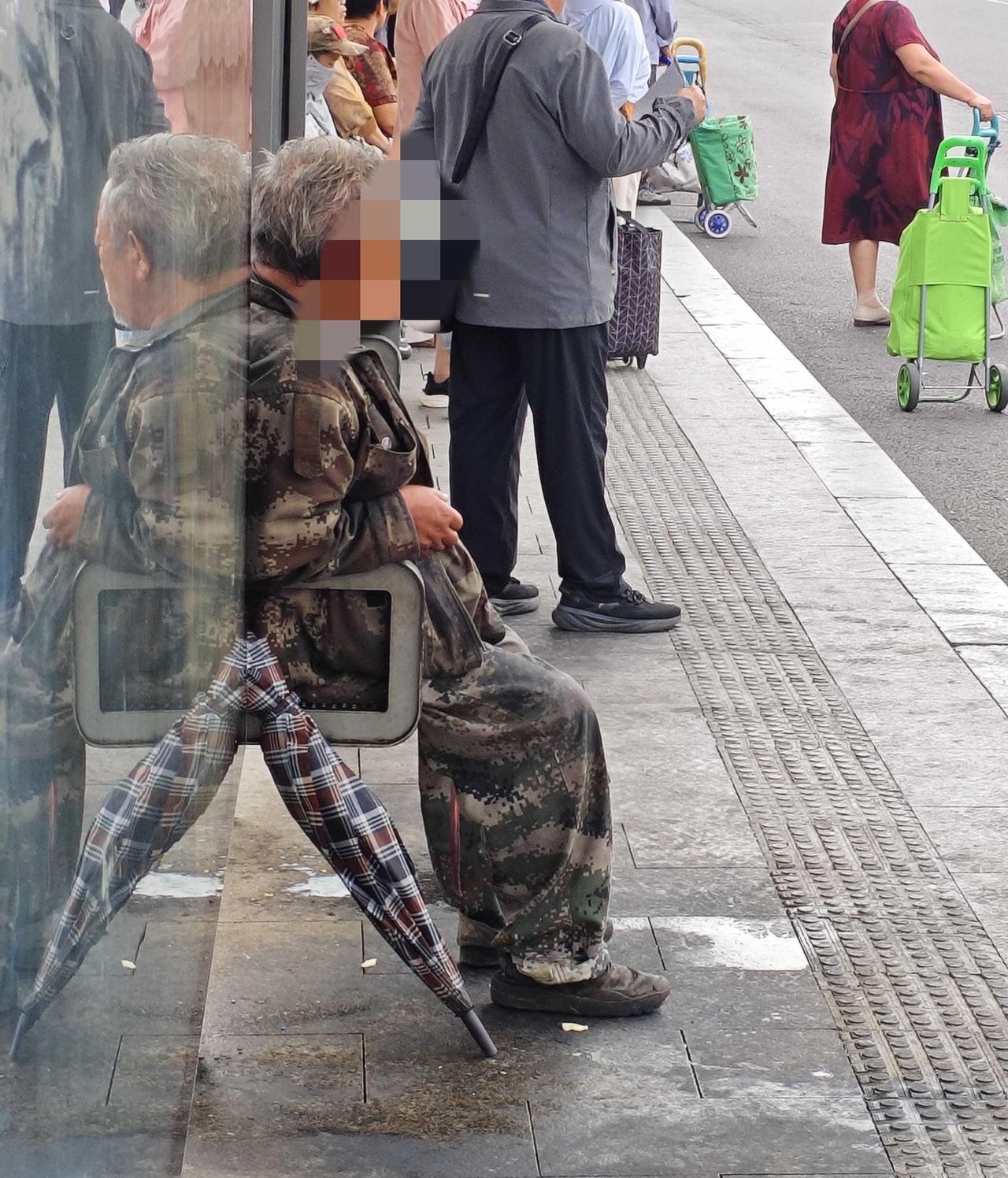 即墨鹤山路服装市场公交站最近总是有个穿迷彩服的男性老年人占着一个座位，旁边还放着