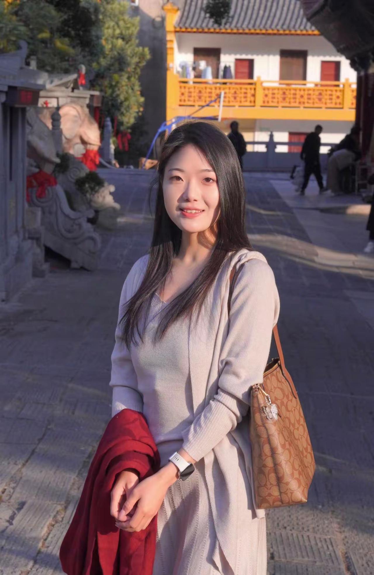 在古风建筑前，优雅少女微笑相伴，红衣与白裙相映成趣。