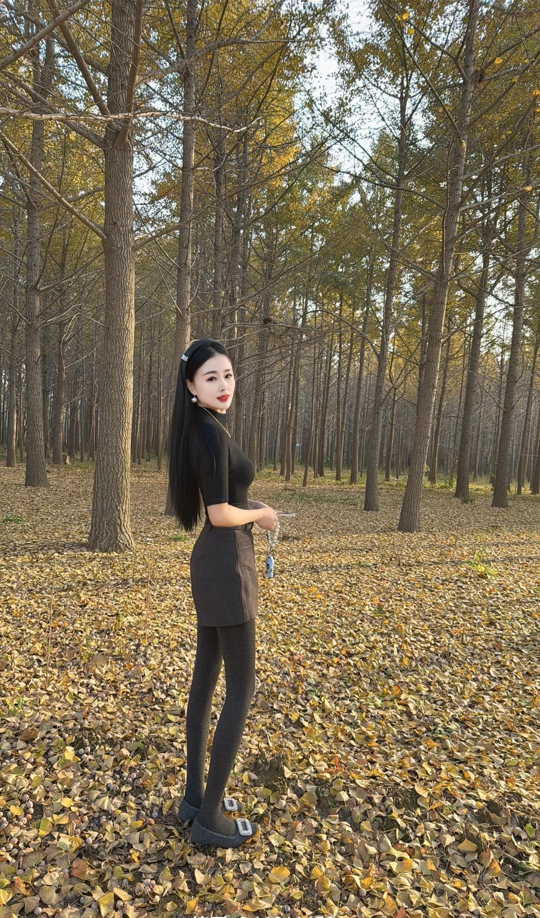 秋日森林里的时尚女孩，黑裙与落叶相映成趣。