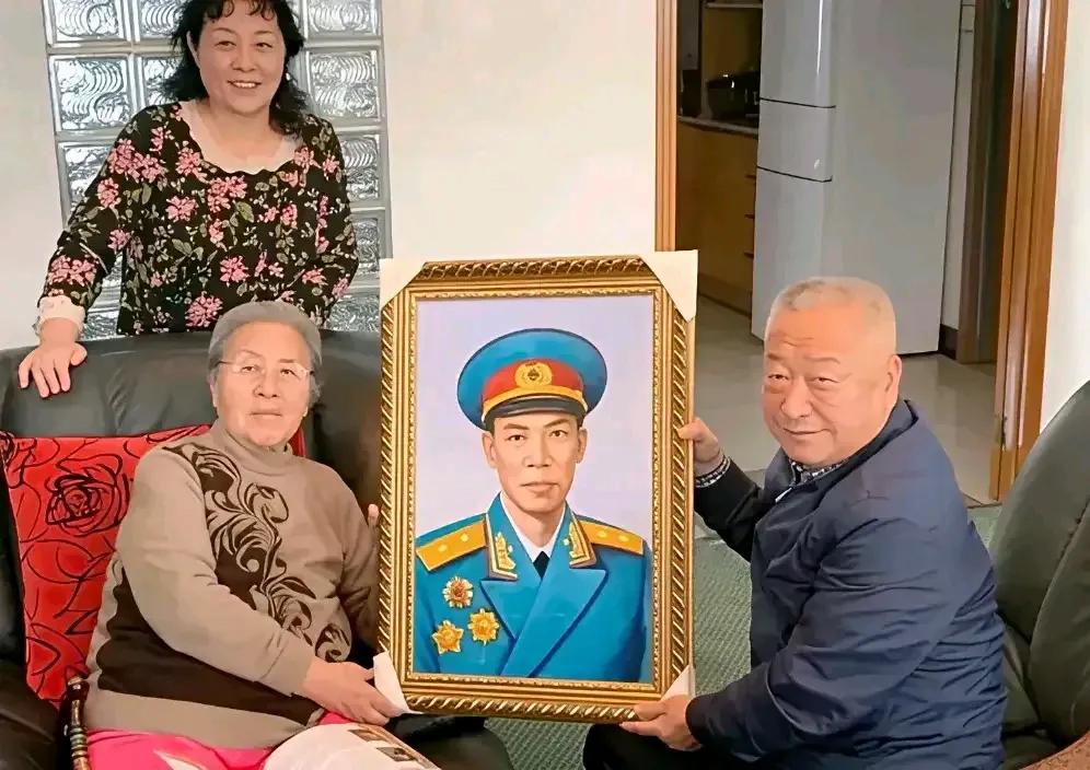 梁兴初将军夫人任桂兰与儿子、女儿手捧将军画像合影留念。梁兴初将军，绰号“梁大牙”