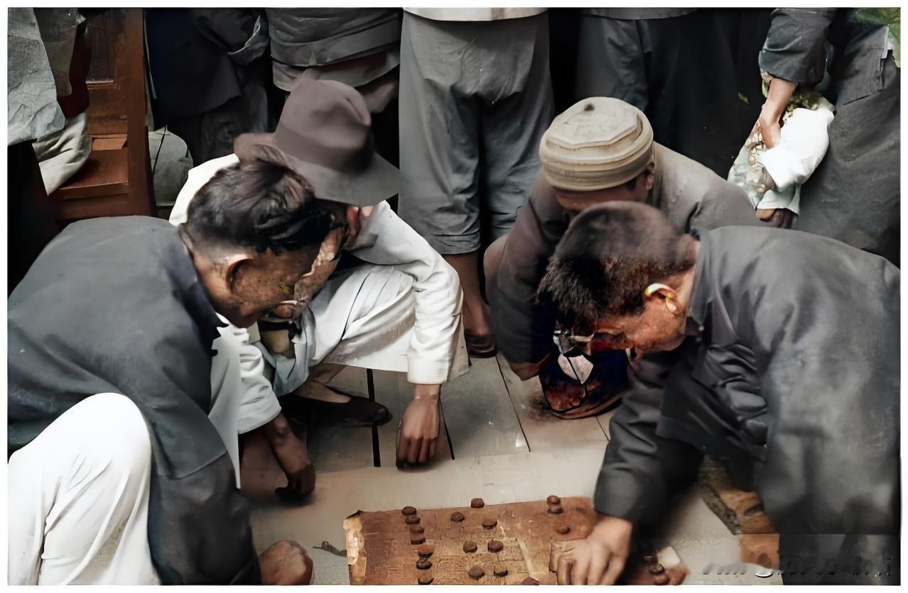 1934年，一群人围聚在路边的棋摊旁，兴致勃勃地观看着两位棋手的激烈对弈。