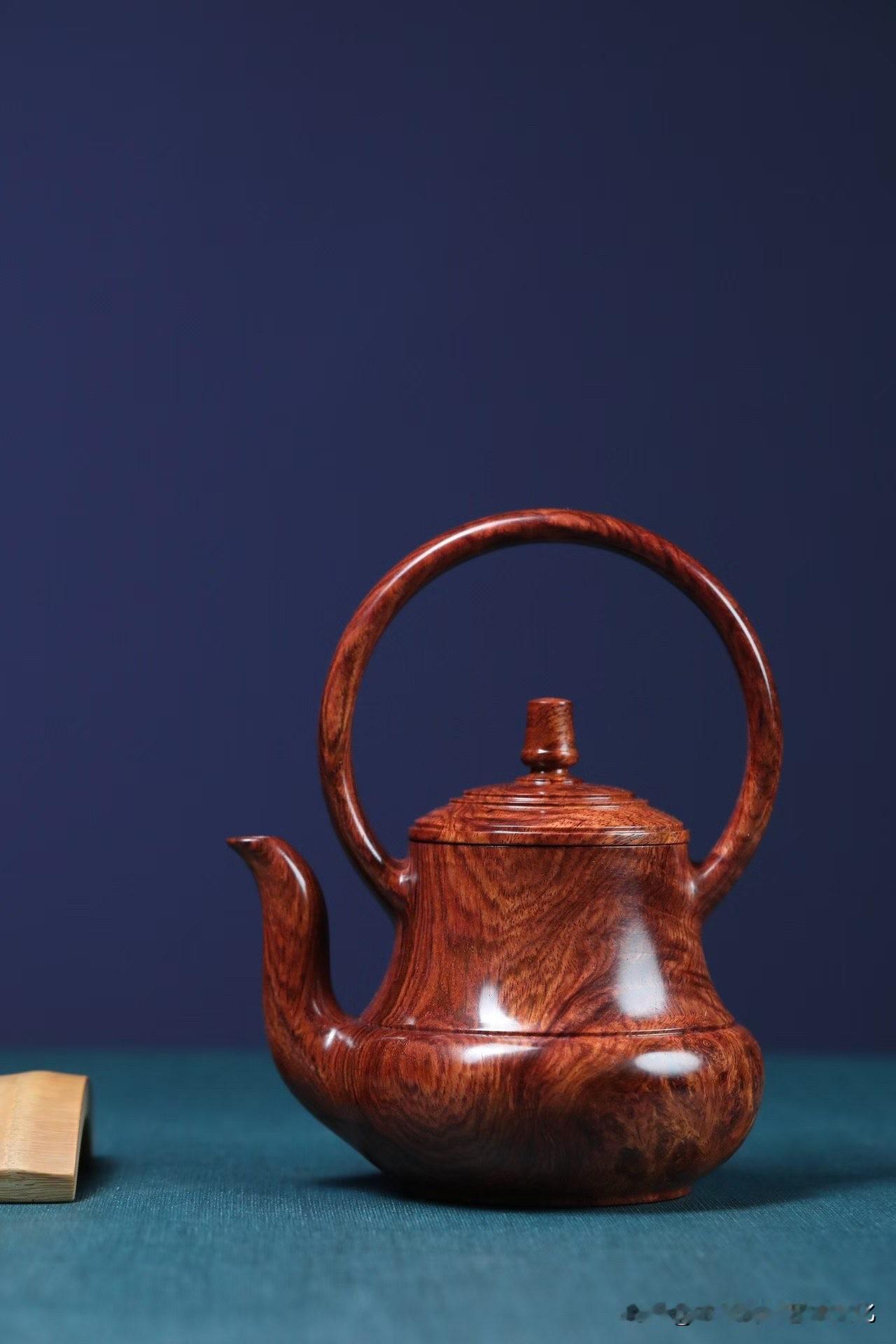 这把提梁壶，不只是器，是一段被收住的水。

黄花梨瘿子料的纹理，像山川回转，
黑