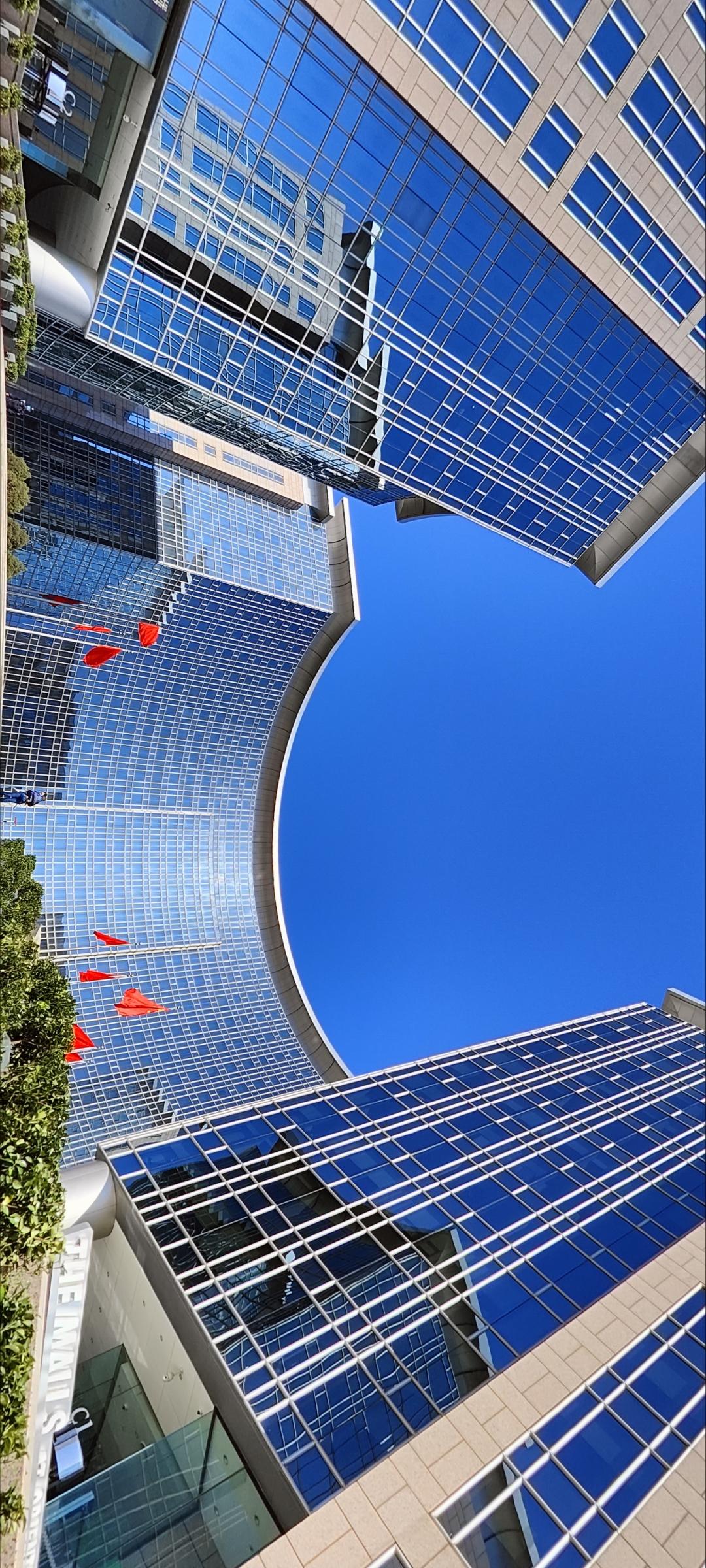 现代都市的玻璃幕墙，蓝天白云映衬下，尽显繁华与未来感。