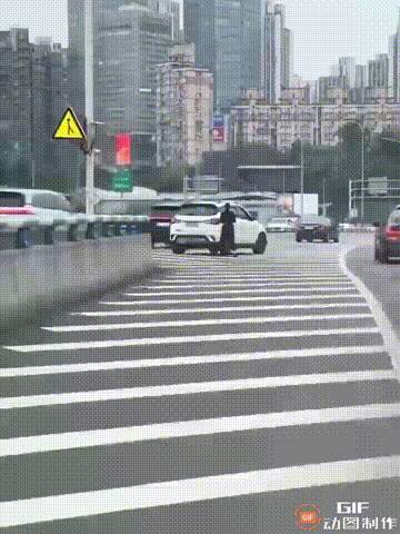 一位网友开车回家时，在途中看见一位女车主把车停在道路汇流处，然后直接在旁边玩起了