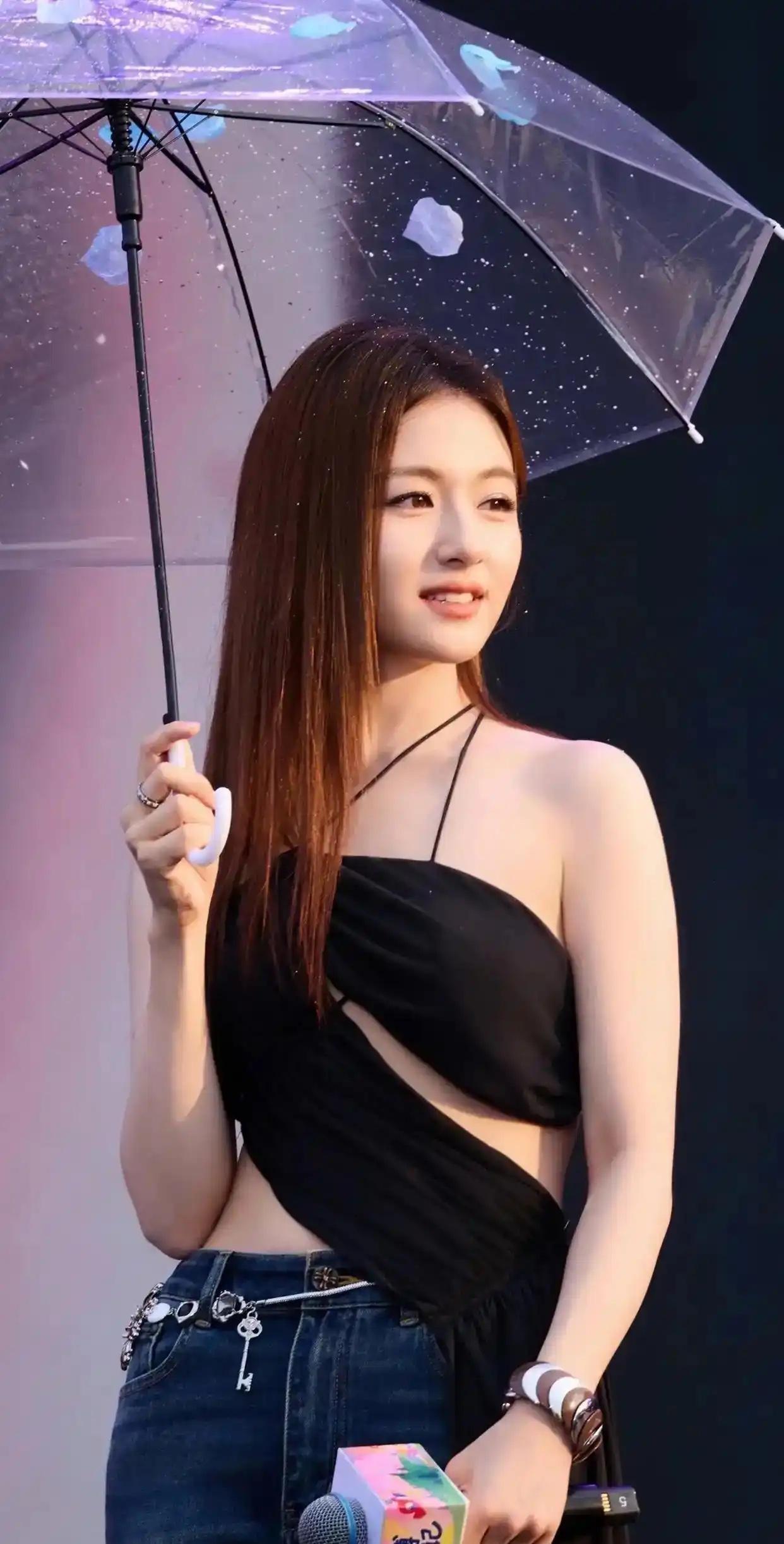 一位美女打着伞，微笑面对镜头。真的是太漂亮了雨后花伞少女 雨中的女子 雨伞下的女