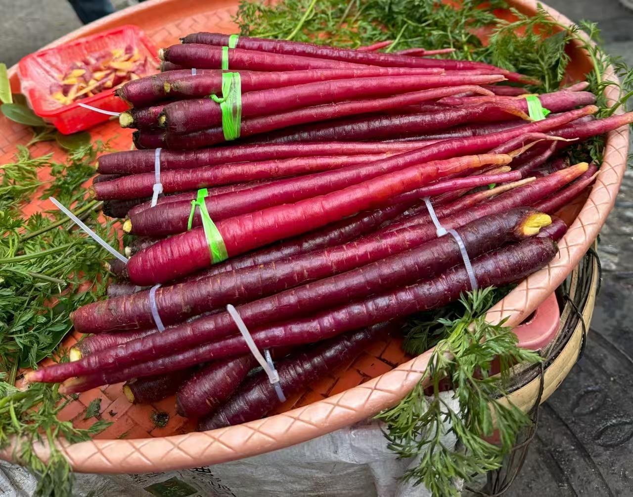 在集市上撞见这一筐紫胡萝卜，瞬间就被惊艳到了！

跟普通胡萝卜比，它红紫透亮的外