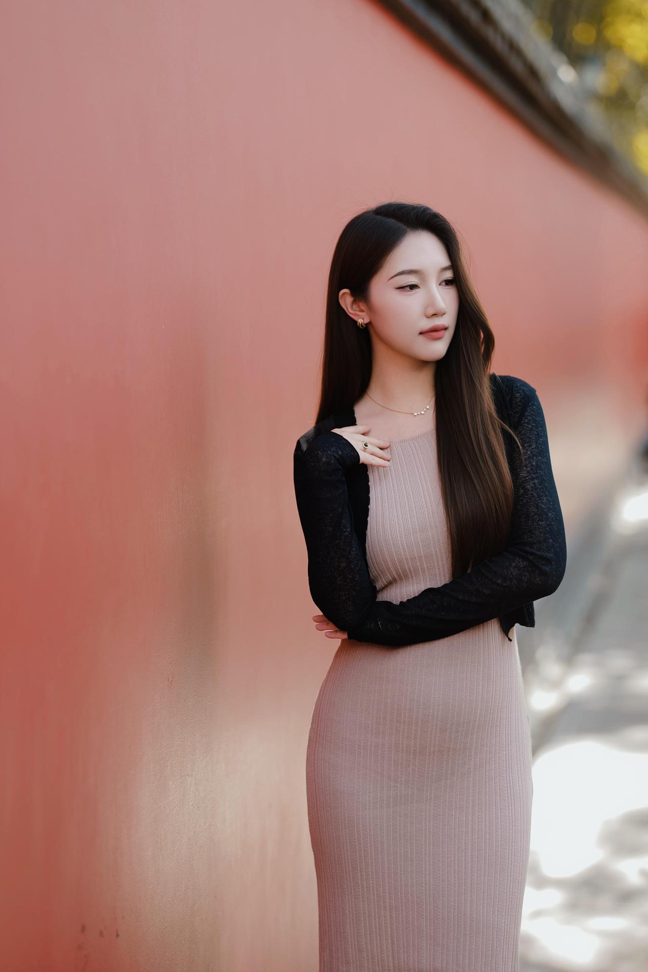 红墙黛瓦，光影斑驳。一袭裸色针织裙，外搭黑开衫，手提白包，在暖光里温柔又明媚，时