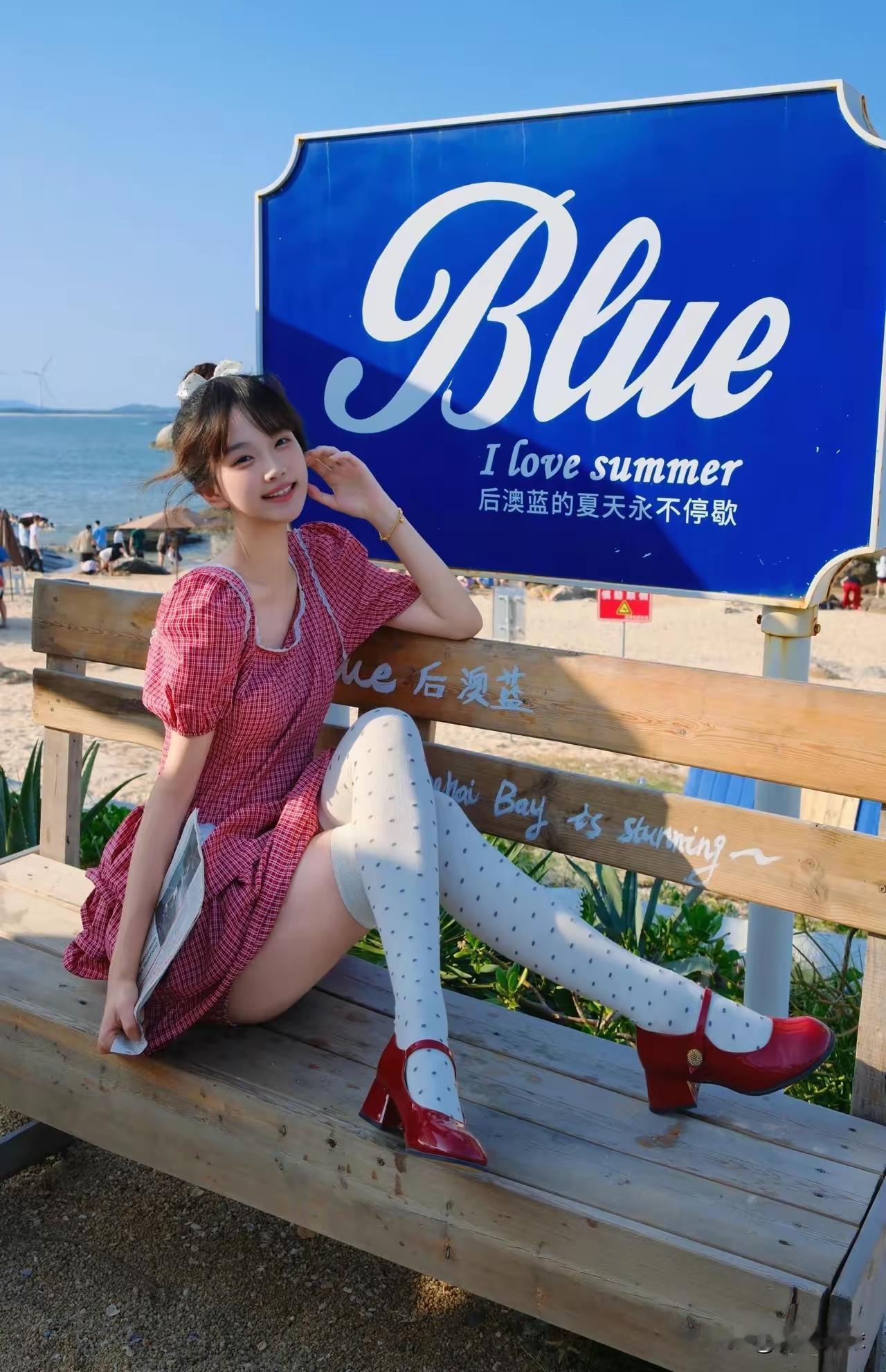夏日海边，穿红裙子的女孩在拍照。