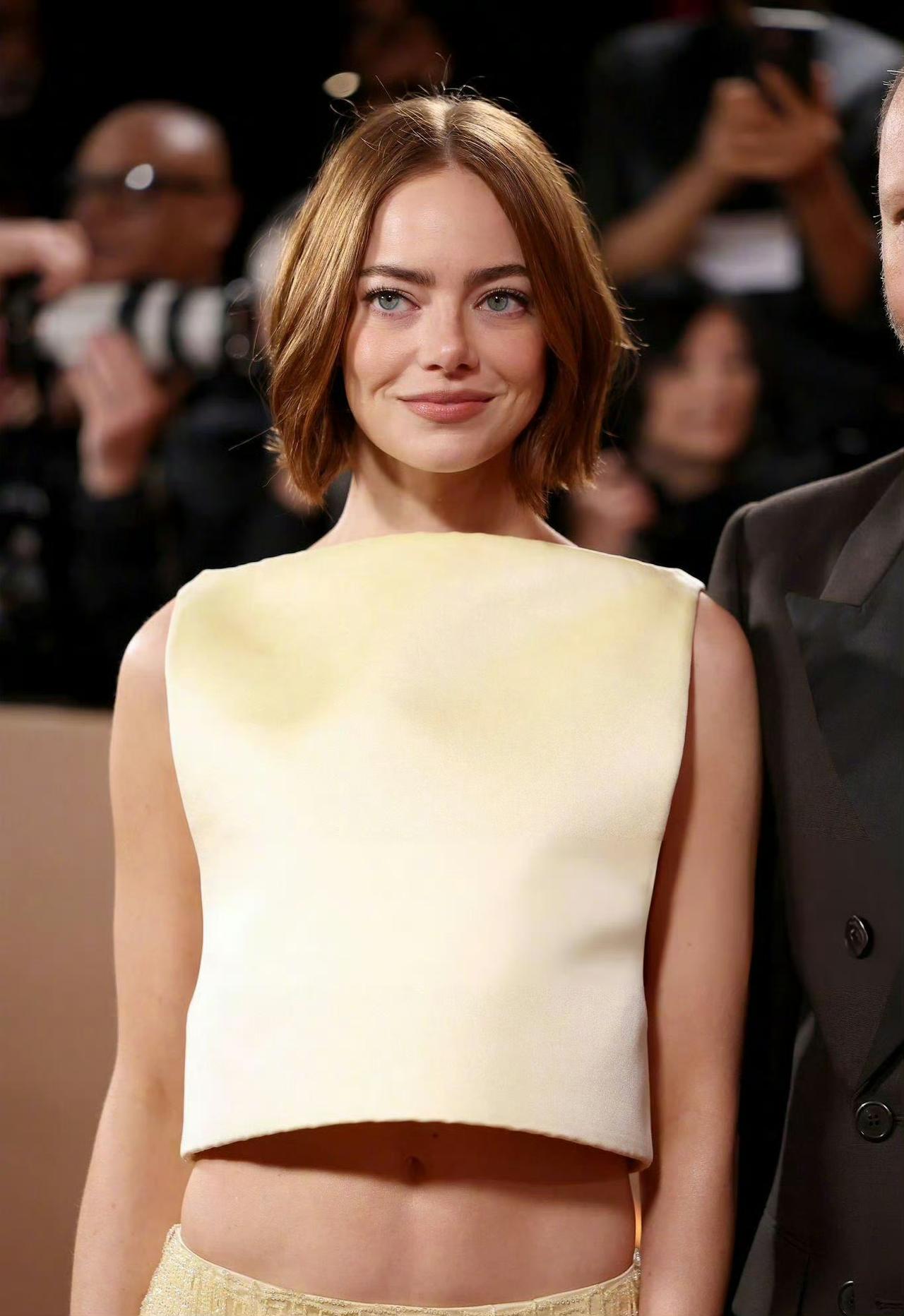 艾玛·斯通身着淡黄色套装与《拯救地球》导演欧格斯·兰斯莫斯一起亮相金球奖红毯，石