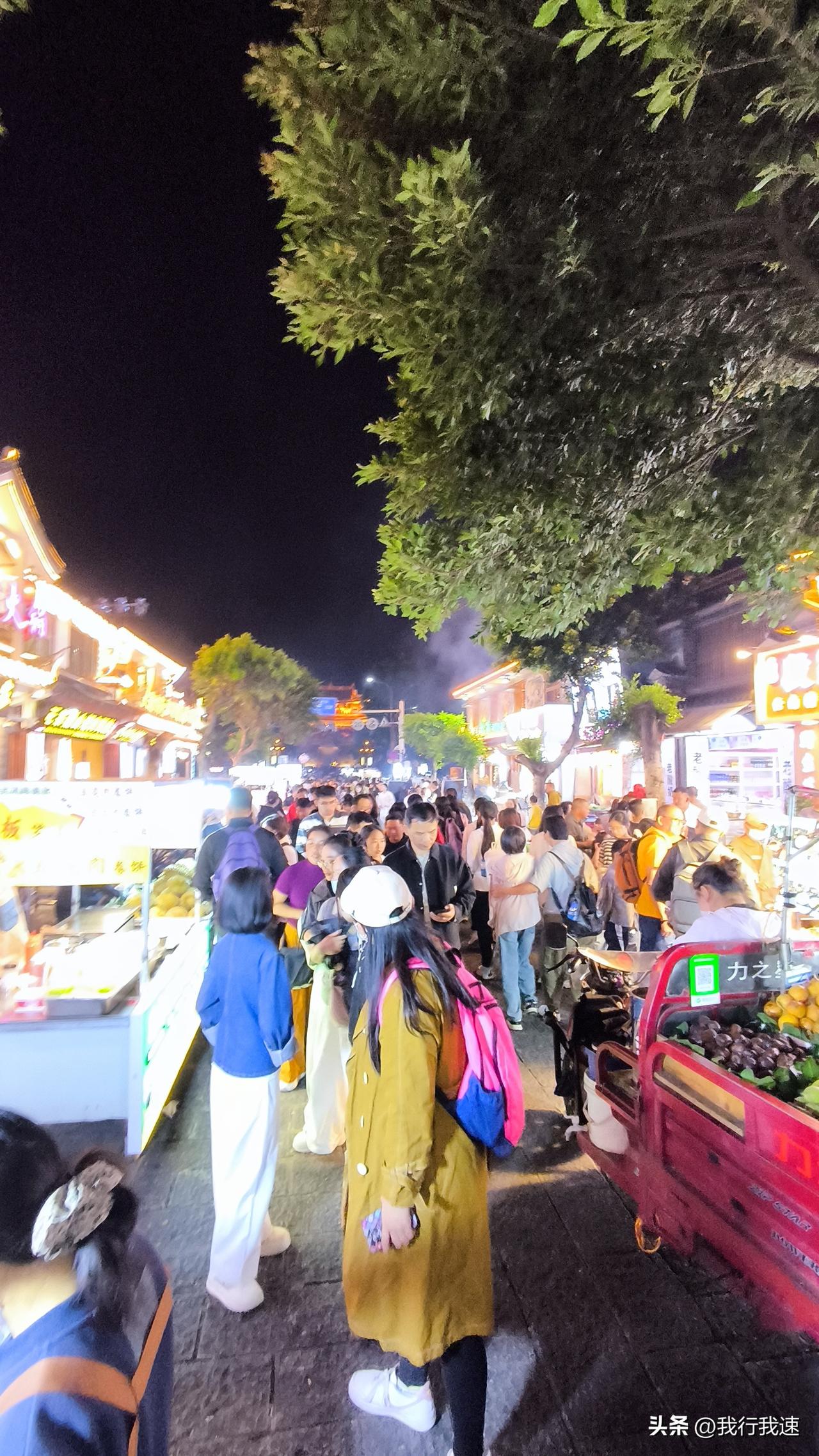 夜市里灯火辉煌，各种摊位琳琅满目。美食摊飘出阵阵香气，烤乳扇甜香软糯，烤饵块口感
