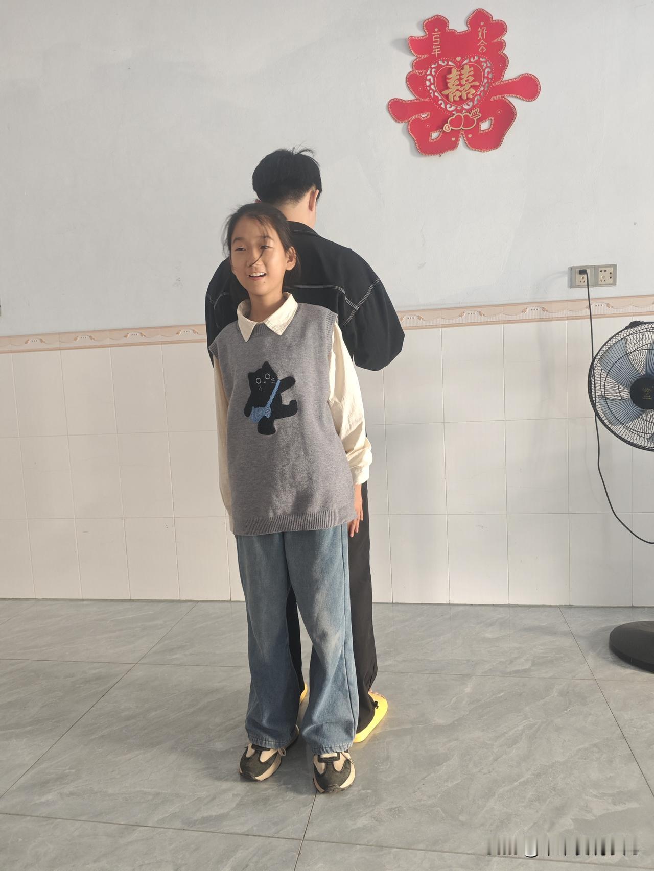 这是一个温暖的午后，阳光透过窗户洒在地板上。小女孩穿着灰色的针织背心，上面有一只