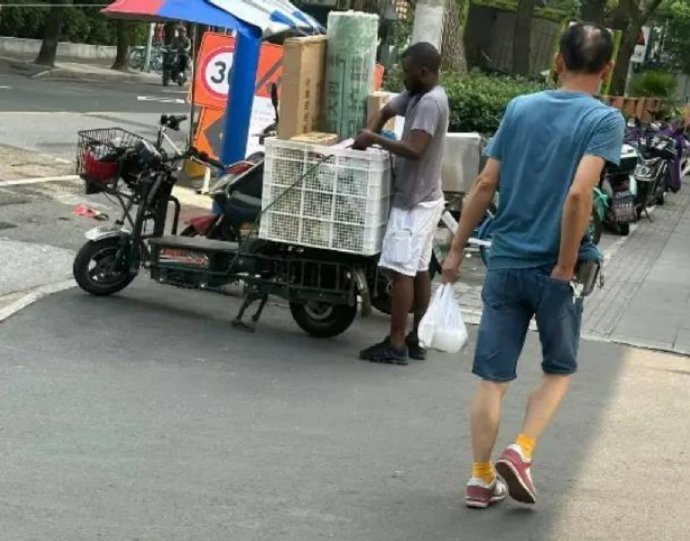 上海街头，一位黑人快递小哥正忙碌着。有人好奇：他有没有劳务答应证？我们不禁要问，
