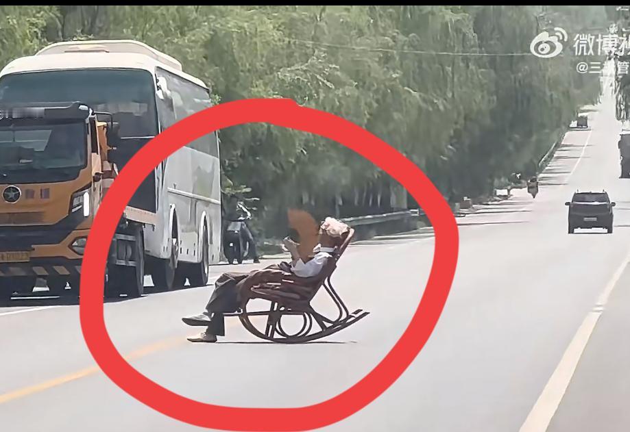 陕西一大爷摇着蒲扇，马路中间晒太阳，这是闹哪一出？一条双向六车道的主干道，大爷一