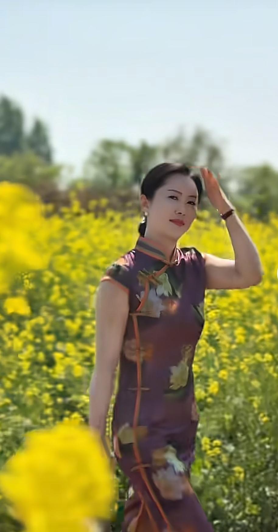 她站在花海里，像从旧时光里走出来的女子，暗紫的绣纹在晴光里泛着温柔的光，发髻挽得