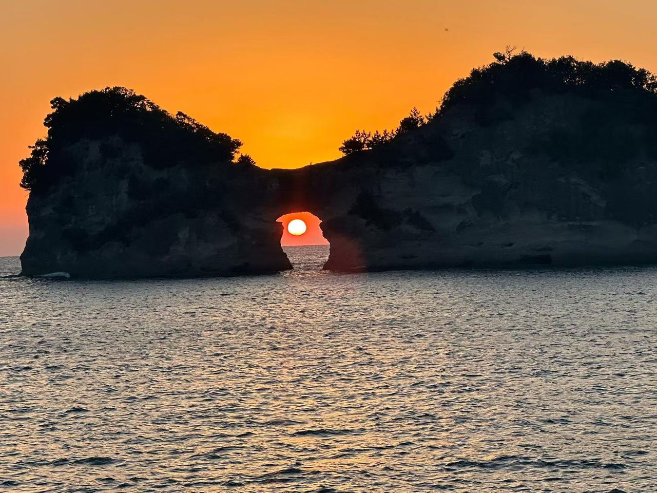 日落时分，海边的岩石拱门映照出绚丽的夕阳，宛如一幅梦幻画卷。