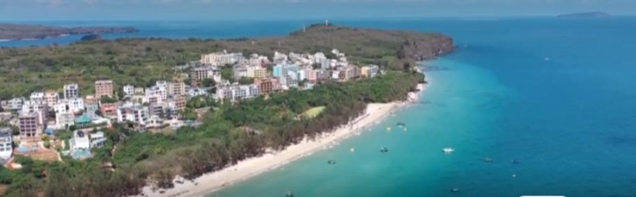 碧海蓝天，礁石与灯塔相映，海风轻扬，海浪拍岸。海面波光粼粼，船只穿梭，海鸥翱翔，