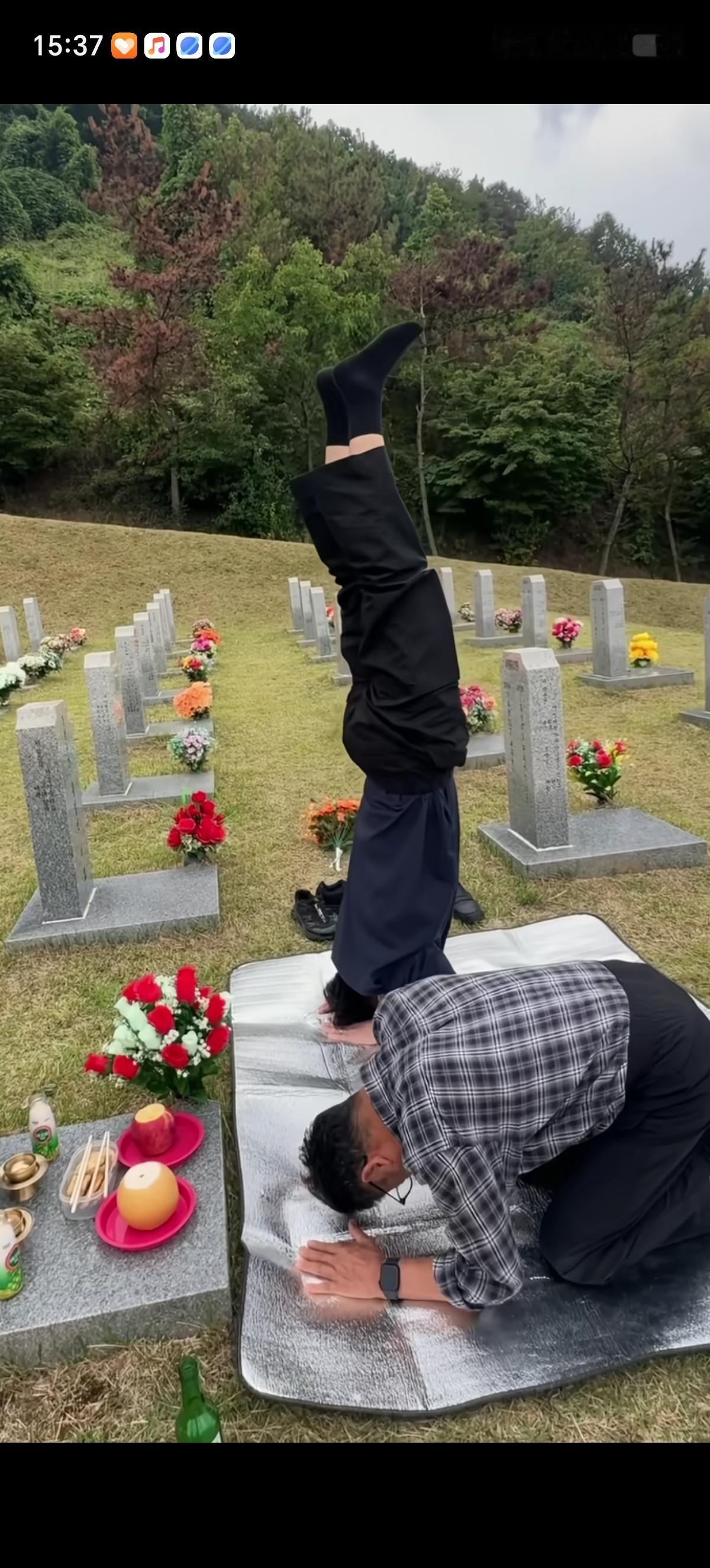 韩国父子俩去祭拜亲人，准备了红色的玫瑰花、苹果、柚子和烧酒、筷子这些贡品。俩人跪