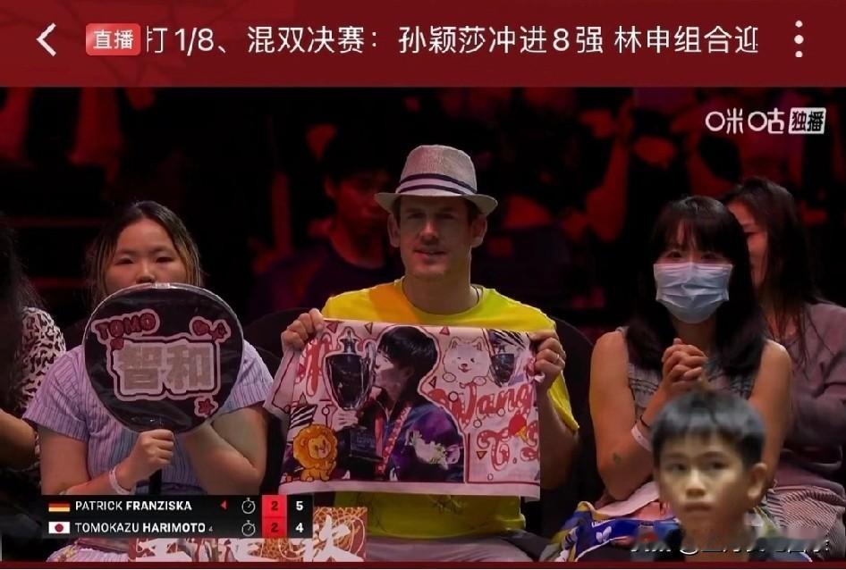 这洋薯条指定受过什么红色教育，在张本智和粉丝旁边，坚定地举着王楚钦的应援毛巾。