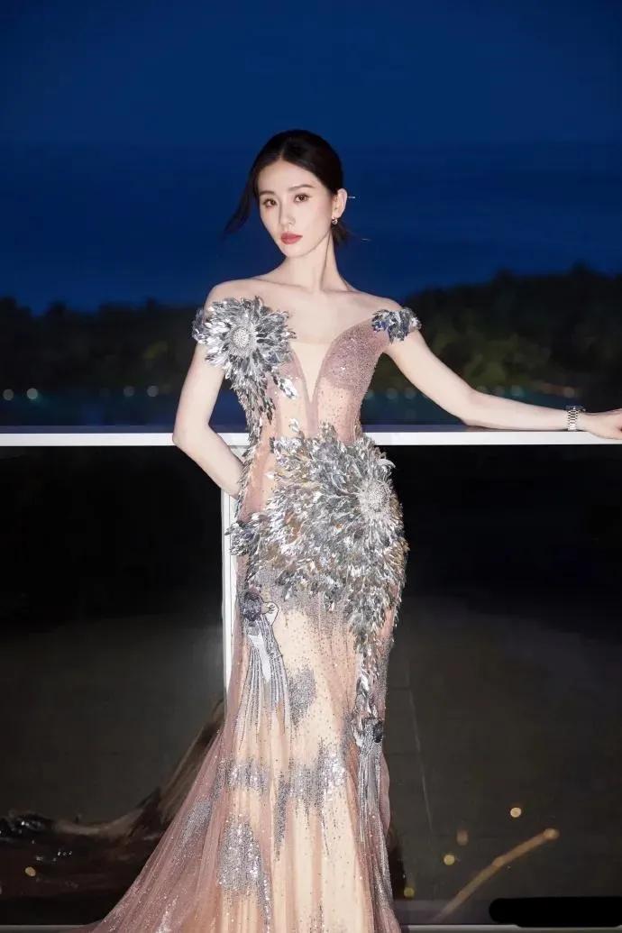 刘诗诗身穿一袭长裙，优雅地站在海边夜景中，海风轻拂，裙摆摇曳生姿。